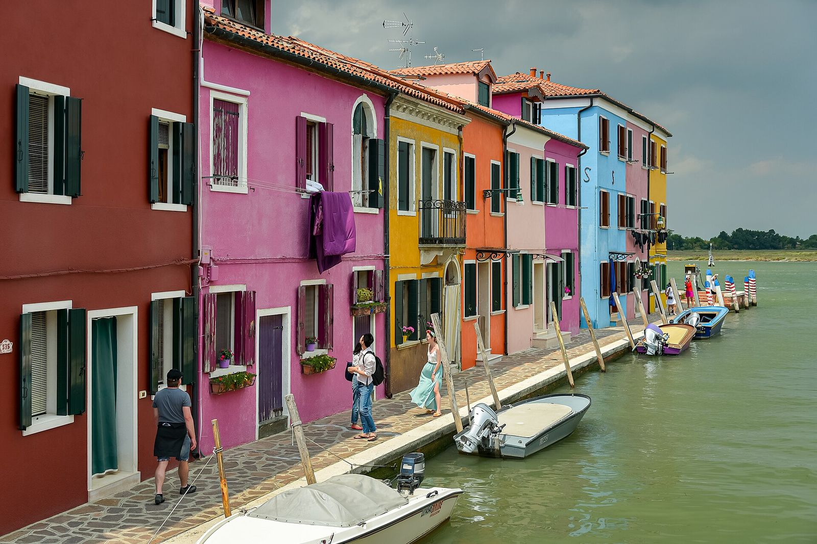 Brightly painted houses in red, pink, yellow and blue along a canal on Burano